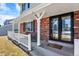 Inviting front porch featuring a seating area, brick accents, and black framed glass front doors at 7631 Oak St, Arvada, CO 80005