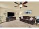Relaxing living room featuring a large screen tv, ceiling fan and comfortable brown sofa at 7631 Oak St, Arvada, CO 80005