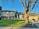 Traditional home featuring a manicured lawn, attached garage, and mature landscaping at 2118 S Mobile Way, Aurora, CO 80013