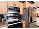 Bright kitchen with black backsplash, wood cabinetry, stainless refrigerator and stainless steel microwave at 5215 S Washington St, Littleton, CO 80121