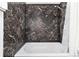 Bathroom featuring a white tub, shower, and marble patterned walls at 1270 N Marion St # 505, Denver, CO 80218