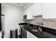Kitchen featuring white cabinets, stainless steel appliances, black countertops, and tile backsplash at 1270 N Marion St # 505, Denver, CO 80218