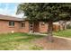 A well-maintained red brick house sits on a grassy lot, shaded by a large pine tree at 3700 Zenobia St, Denver, CO 80212