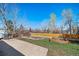 Spacious backyard with garden beds, mature trees, and a concrete patio, perfect for outdoor living at 9231 W Louisiana Ave, Lakewood, CO 80232