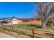 Front exterior featuring a well maintained home, lawn, mature trees, and a classic wooden fence at 9231 W Louisiana Ave, Lakewood, CO 80232