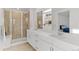 Bright bathroom featuring a glass shower, double vanity with white countertops, and neutral-toned tile floor at 23820 E 34Th Ave, Aurora, CO 80019