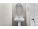 Stylish powder room featuring a pedestal sink, decorative mirror, and modern fixtures at 11918 Mountview Ln, Broomfield, CO 80021