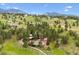 Aerial view of the picturesque property surrounded by lush greenery, mountains, and well-maintained grounds at 33208 Alta Vista Dr, Evergreen, CO 80439