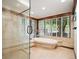 Bright bathroom with a soaking tub, walk-in shower and large windows with views of the backyard at 33208 Alta Vista Dr, Evergreen, CO 80439