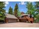 Spacious exterior showcases a three-car garage, wooden decks, and a charming mountain aesthetic at 33208 Alta Vista Dr, Evergreen, CO 80439