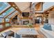 Cozy living room featuring a stone fireplace, wood floors, a comfortable seating area, and beautiful window views at 33208 Alta Vista Dr, Evergreen, CO 80439