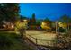 Illuminated tennis court for nighttime play; surrounded by lush trees and a scenic hillside at 33208 Alta Vista Dr, Evergreen, CO 80439