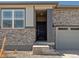 Front entrance with stone exterior, steps, and dark-colored door at 6050 Hourglass Dr, Brighton, CO 80601