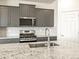 Well-equipped kitchen with stainless steel appliances, gray cabinets, granite countertops and stylish backsplash design at 6050 Hourglass Dr, Brighton, CO 80601