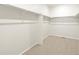 Spacious walk-in closet featuring neutral carpet, ample shelving, and bright, white walls at 6050 Hourglass Dr, Brighton, CO 80601
