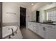 Elegant bathroom featuring dual sinks, white cabinets, tile floor, soaking tub, and walk-in closet access at 8230 S White Crow St, Aurora, CO 80016