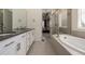 Bright bathroom showcasing dual sinks, white cabinets, soaking tub, walk-in shower and bedroom access at 8230 S White Crow St, Aurora, CO 80016
