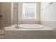 Relaxing bathroom featuring a soaking tub, tiled walls, and glass-enclosed shower with bright natural light at 8230 S White Crow St, Aurora, CO 80016
