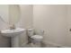 Powder room with pedestal sink, round mirror, and neutral color palette at 8230 S White Crow St, Aurora, CO 80016