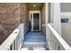 Covered front entryway with brick wall detail, concrete stairs and wooden door leading into the home at 8230 S White Crow St, Aurora, CO 80016