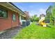 A grassy backyard features a small playground, AC Unit, chimney, and access to the home at 5200 W Rowland Ave, Littleton, CO 80128
