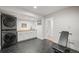 Modern laundry room with black tile flooring, stacked washer/dryer, sink, cabinets, and gym equipment at 5200 W Rowland Ave, Littleton, CO 80128