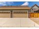 Beige two car garage with brick accents and a large concrete driveway and address numbers at 14065 Harrison St, Thornton, CO 80602