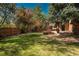 Expansive backyard with a lush lawn, mature trees, and an outdoor entertaining area under a pergola at 5000 S Chester St, Greenwood Village, CO 80111