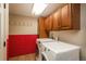 Laundry room with front-load machines, red tile accent wall, built-in cabinets, and utility lighting at 5000 S Chester St, Greenwood Village, CO 80111