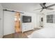 Bright main bedroom featuring a barn door to bathroom, ceiling fan, and built-in wardrobe with full-length mirror at 5000 S Chester St, Greenwood Village, CO 80111