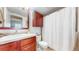A cozy bathroom features cherry wood cabinets and vanity, white countertops, and a shower with a curtain at 601 W 11Th Ave # 1109, Denver, CO 80204
