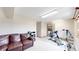 Spacious living room area with a leather sofa, exercise equipment, and natural light at 7208 Secrest Ct, Arvada, CO 80007