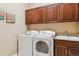 Well-lit laundry room featuring a washer, dryer, utility sink, storage cabinets, and tile backsplash at 6711 S Catawba Way, Aurora, CO 80016