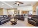 Open-concept living room featuring leather furniture, a ceiling fan, and hardwood floors flowing into the kitchen area at 6711 S Catawba Way, Aurora, CO 80016