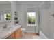 Well-lit bathroom featuring a combination tub and shower, vanity, and a large window providing natural light at 3212 Fulton St, Denver, CO 80238