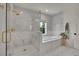Bright bathroom featuring a glass-enclosed shower and separate soaking tub, marble tile, and elegant gold fixtures at 3212 Fulton St, Denver, CO 80238