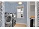 Modern laundry room featuring front-load washer and dryer, stylish wallpaper, and ample storage space at 3212 Fulton St, Denver, CO 80238