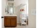 Bathroom with a wood vanity, sleek mirror, and decorative shelving for storage and style at 3567 E 140Th Dr, Thornton, CO 80602
