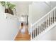 Bright hallway featuring hardwood floors, white walls, staircase, and access to dining area at 3567 E 140Th Dr, Thornton, CO 80602