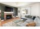 Cozy living room featuring a stone fireplace, large window, and comfortable sectional sofa at 3567 E 140Th Dr, Thornton, CO 80602