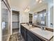 Bathroom featuring double sinks, large mirror, walk-in shower and walk-in closet at 5188 Andes Way, Denver, CO 80249