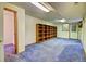 A spacious basement with blue carpet, a door to the outside, and a large bookshelf at 11540 Inspiration Rd, Golden, CO 80403