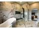 Modern bathroom with a luxurious soaking tub, marble tile and glass enclosed shower with bench at 3530 Doolittle Rd, Monument, CO 80132