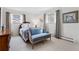 Bright bedroom featuring a comfortable bed, a stylish loveseat, and natural light from two windows at 3680 S Pontiac Way, Denver, CO 80237