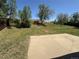 A serene backyard featuring green grass, mature trees, and a concrete patio at 8491 W Star Cir, Littleton, CO 80128