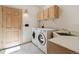 Bright laundry room with a washer, dryer, utility sink, and wooden storage cabinets at 1123 Oakhurst Dr, Broomfield, CO 80020