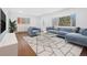 Bright living room with large bay window, comfortable blue seating and a modern geometric-patterned rug at 5730 E 19Th Ave, Denver, CO 80220