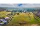 Wide aerial shot showing vast green acreage with scattered buildings, trees, and a community visible in the background at 5800 W Bowles Ave, Littleton, CO 80123
