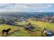Beautiful aerial view of a large property featuring green fields, mature trees, and a charming home; community in the background at 5800 W Bowles Ave, Littleton, CO 80123
