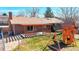 The backyard features a wooden pergola, a grassy lawn, a brick house and a wooden playset at 3387 S Pitkin Way, Aurora, CO 80013